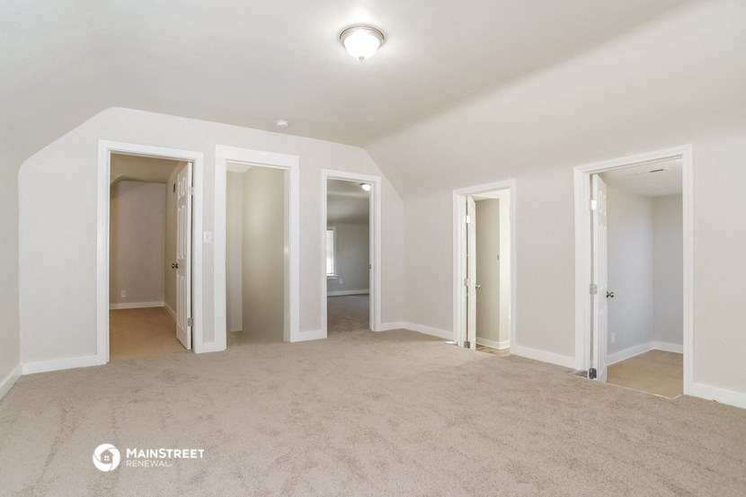an empty living room with four doors and a carpeted floor