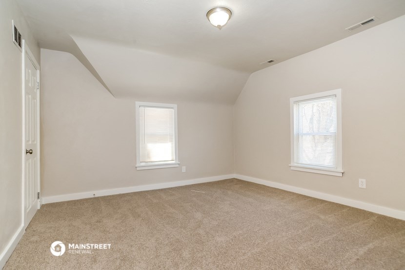 the spacious upstairs bedroom with carpeting and two windows