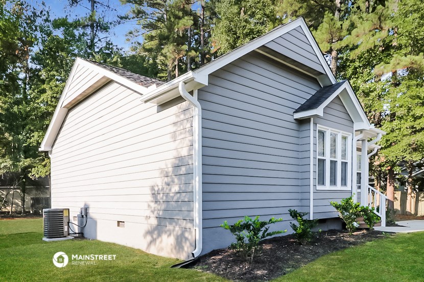a white house with white siding and a lawn and trees