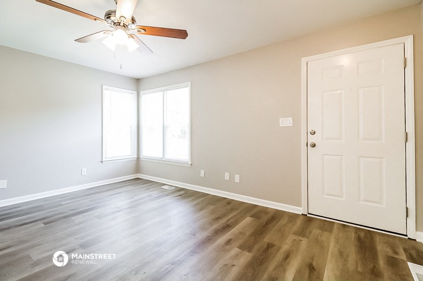 an empty living room with wood floors and a ceiling fan
