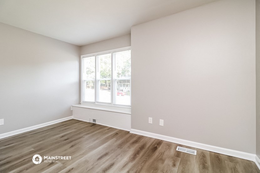 the living room of an apartment with wood flooring and a window