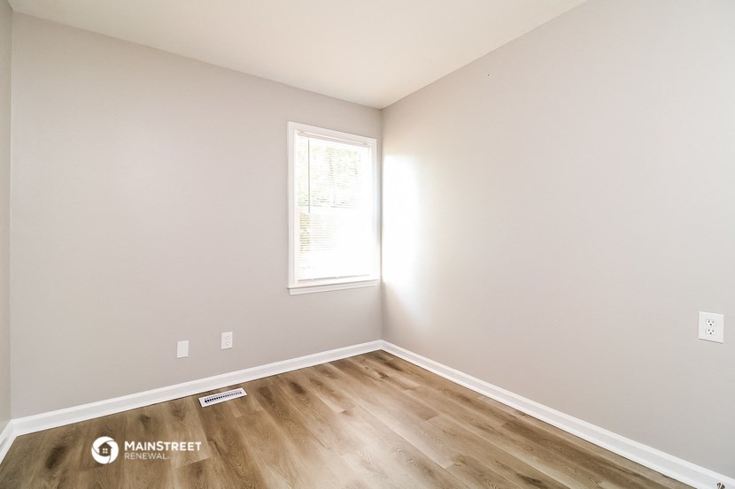 an empty room with wooden floors and a window