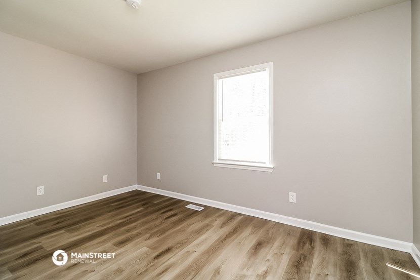an empty room with wooden floors and a window