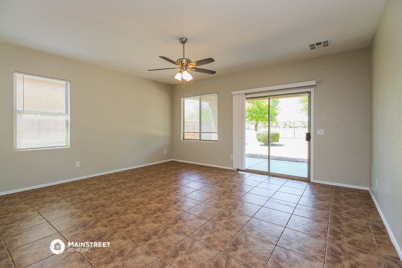 an empty living room with a ceiling fan and a sliding glass door