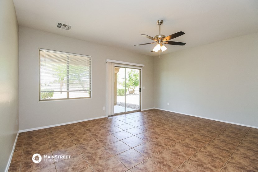 an empty living room with a ceiling fan and a window