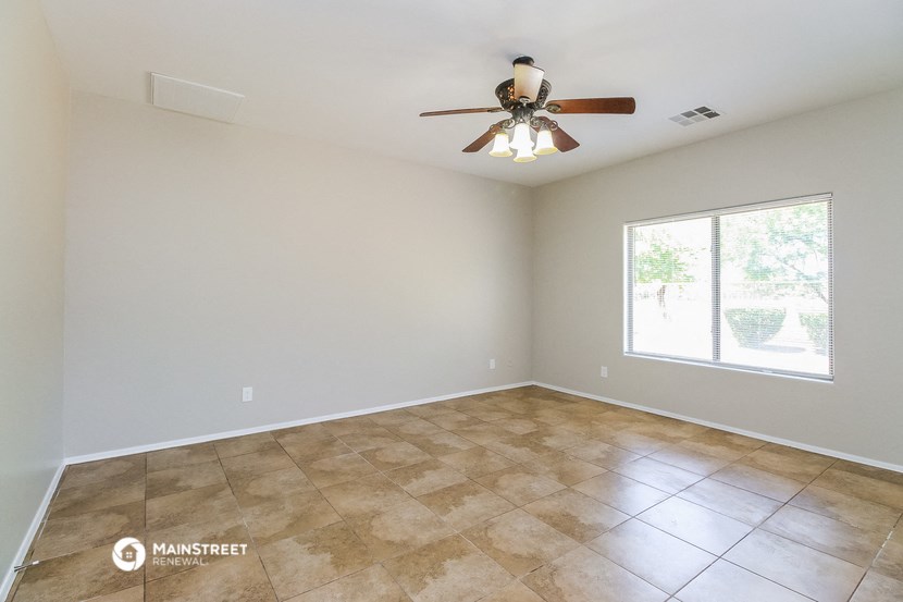 a empty living room with a ceiling fan and a window