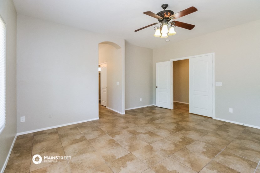 the spacious living room with ceiling fan and tile flooring