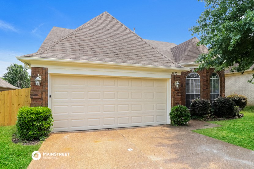 a white garage door in front of a brick house