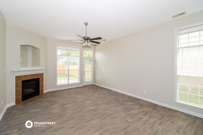 a living room with a fireplace and a ceiling fan