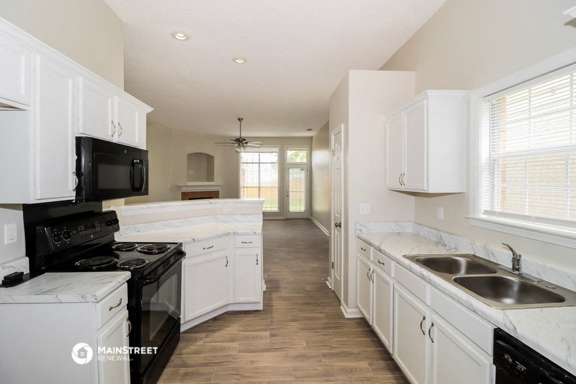 an empty kitchen with white cabinets and a black stove and microwave