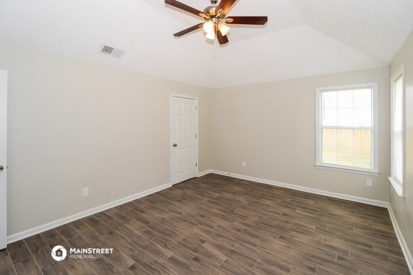 the spacious living room with wood flooring and a ceiling fan