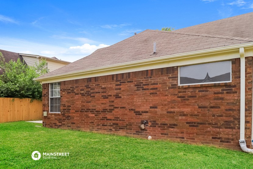 the front of a brick house with a yard and grass