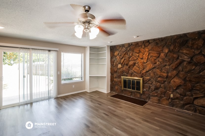 a living room with a stone wall and a ceiling fan