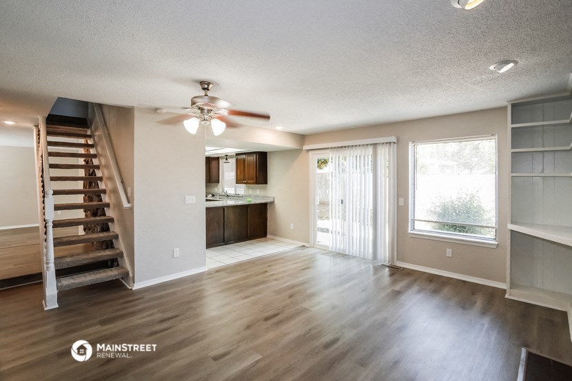 an empty living room with a staircase and a kitchen