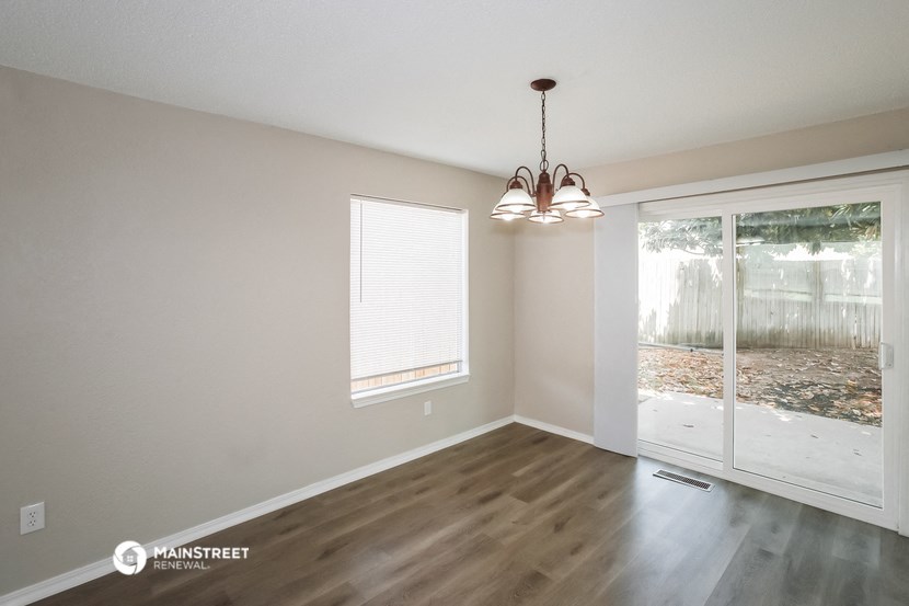 an empty living room with a sliding glass door to the backyard