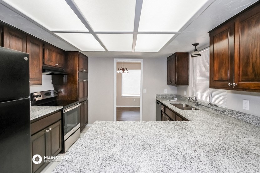 a kitchen with white granite counter tops and wooden cabinets