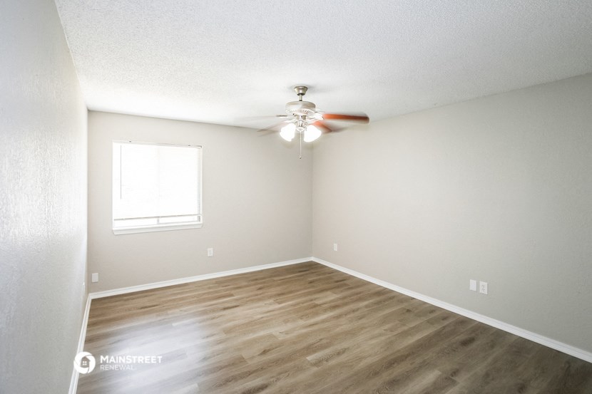 an empty room with a ceiling fan and a window