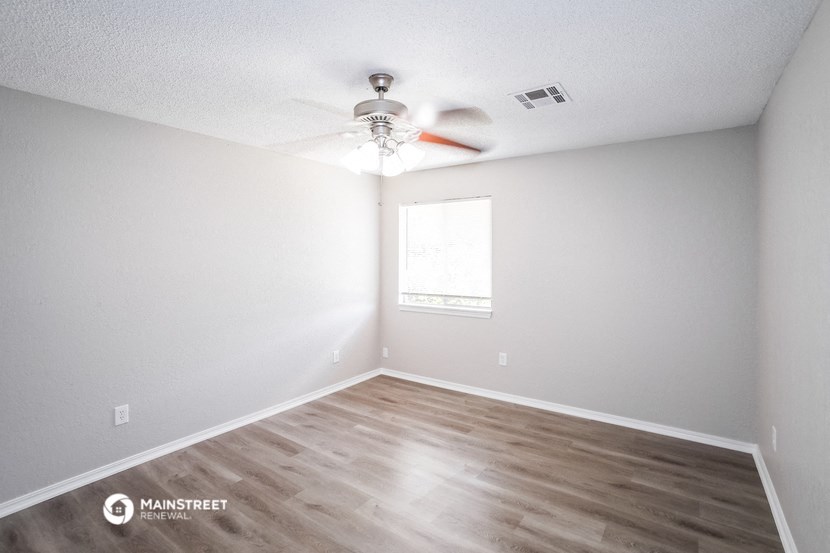 an empty room with a ceiling fan and a window
