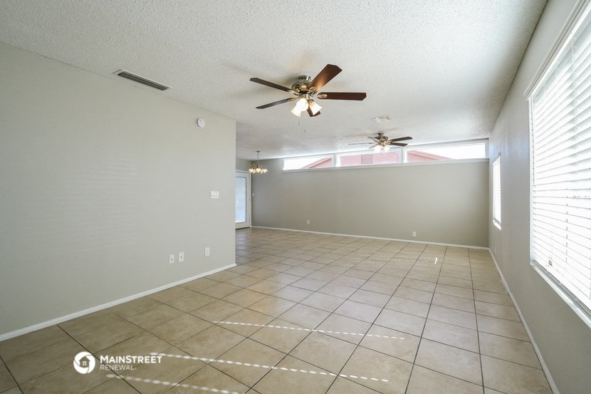 a empty living room with a ceiling fan and a tiled floor