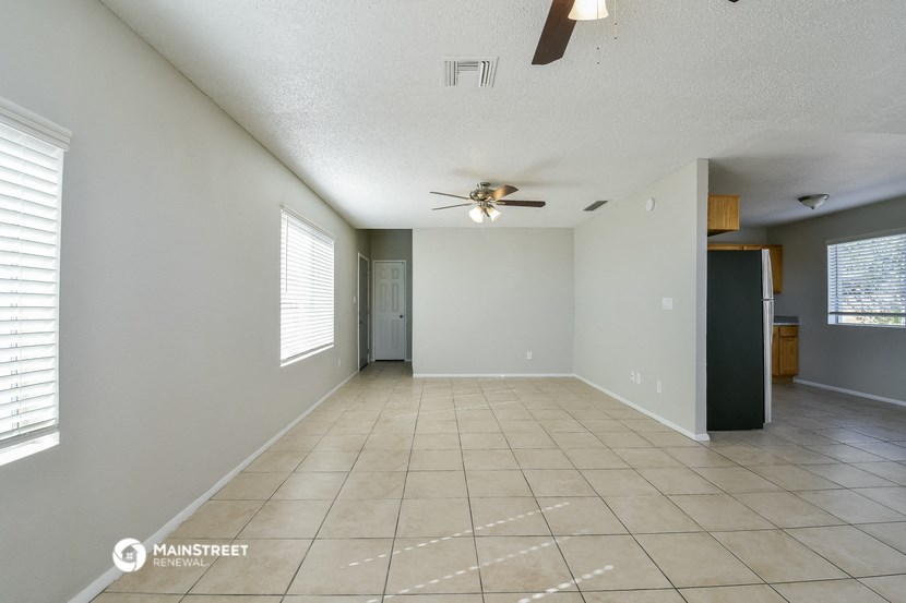 an empty living room with a ceiling fan and a tiled floor