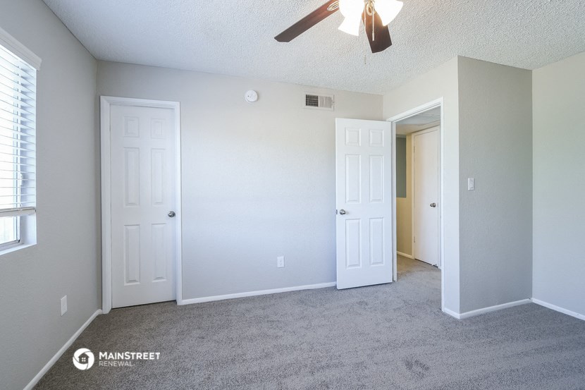 an empty room with two doors and a ceiling fan