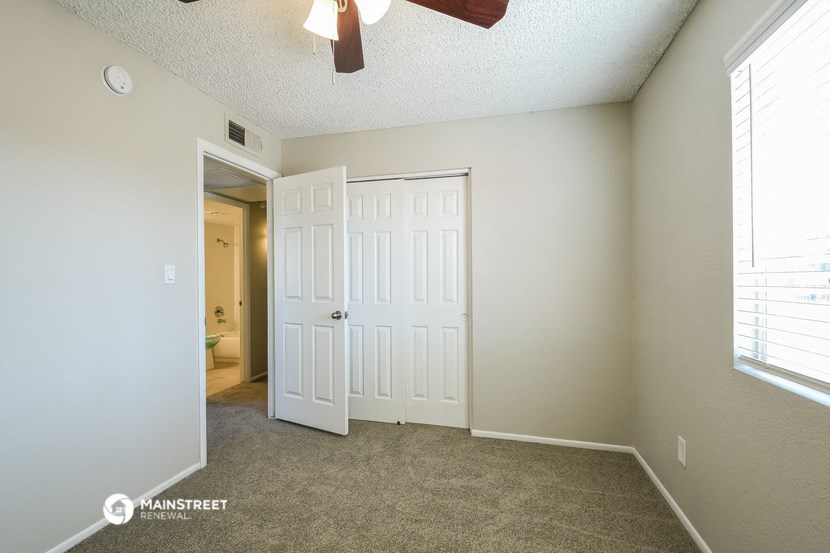 the living room of an apartment with a closet and a door to the bathroom
