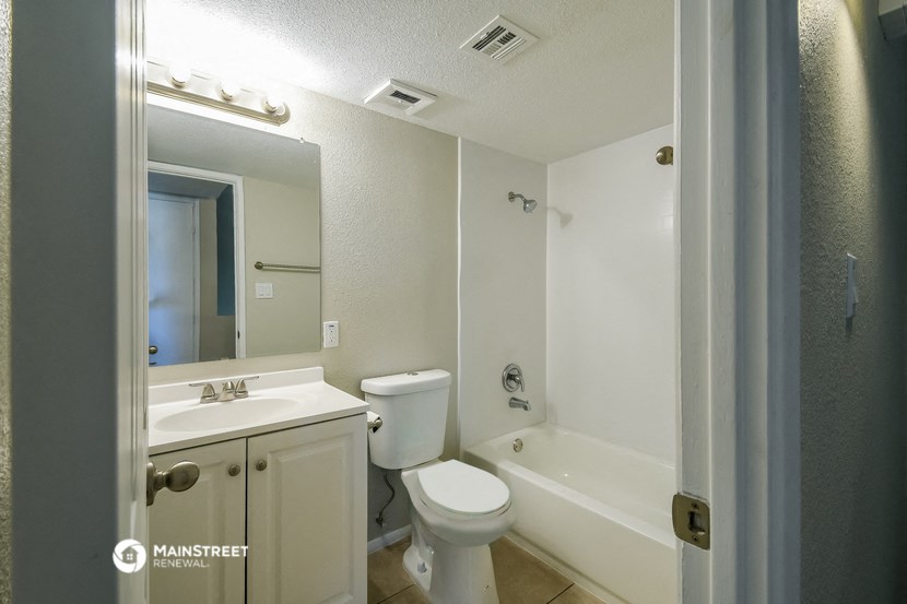 a bathroom with a toilet sink and tub and a mirror