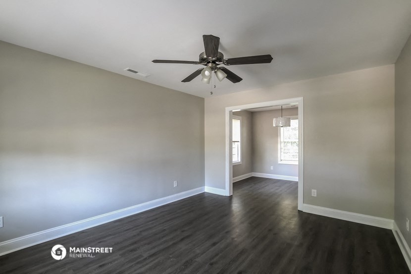 a living room with wood floors and a ceiling fan