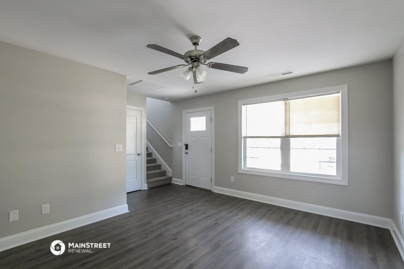 an empty living room with a ceiling fan and a window