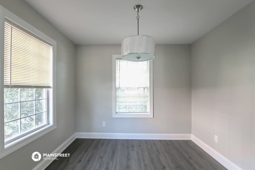 an empty room with two windows and a lamp