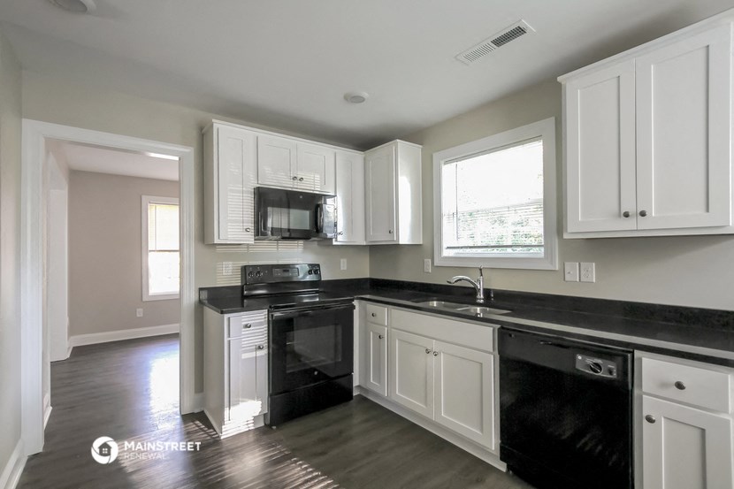 a kitchen with white cabinets and black counter tops