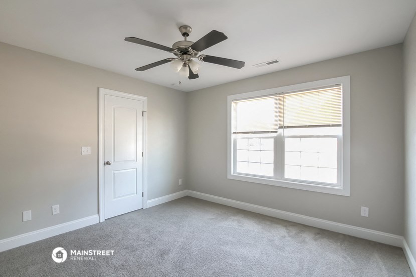 an empty room with a ceiling fan and a window