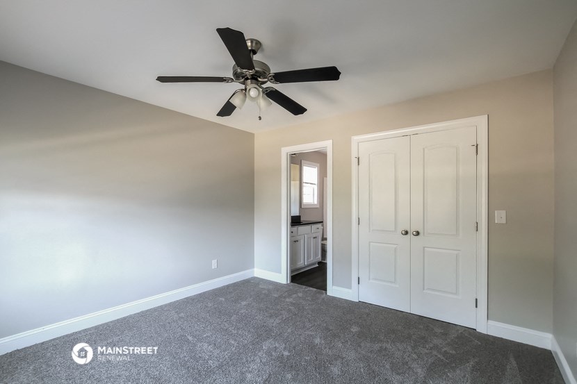 an empty living room with a ceiling fan and a closet