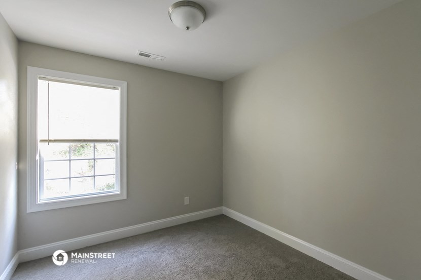 an empty room with a window and carpet
