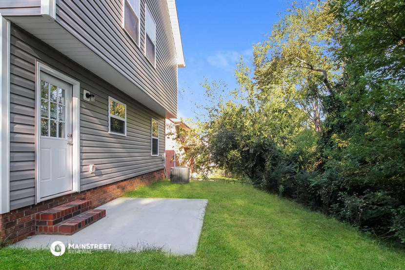 the back of a house with a yard and a white door