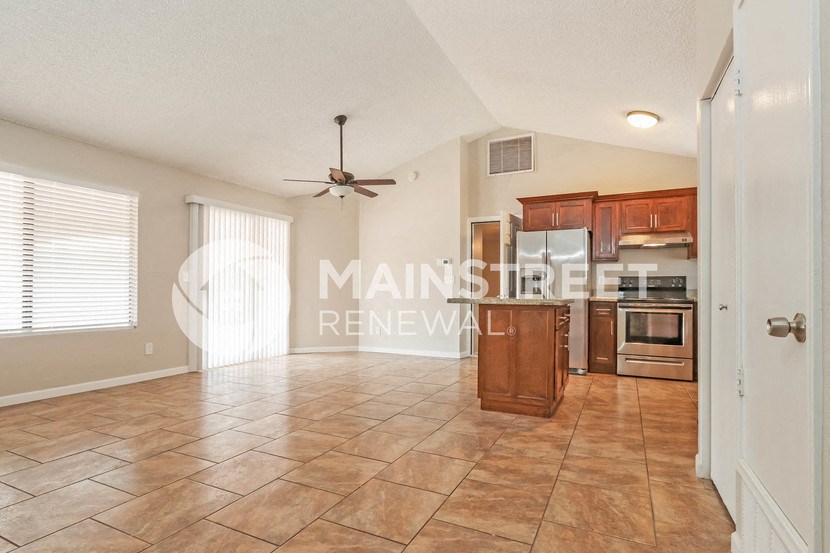 a large living room with a kitchen and a ceiling fan