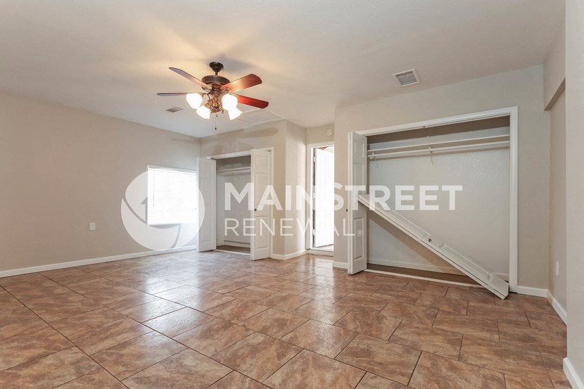 a large empty living room with a closet and a ceiling fan