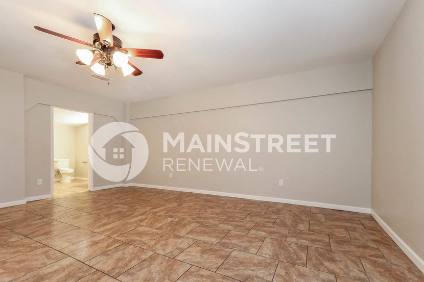 a spacious living room with a ceiling fan and tile floor