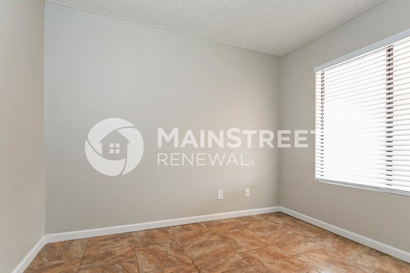 a bedroom with a large window and tile floor