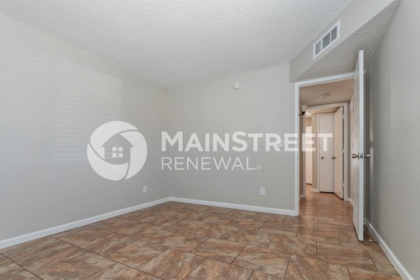 a renovated living room with tile flooring and a door to a hallway