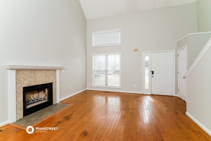the living room with wood floors and a fireplace