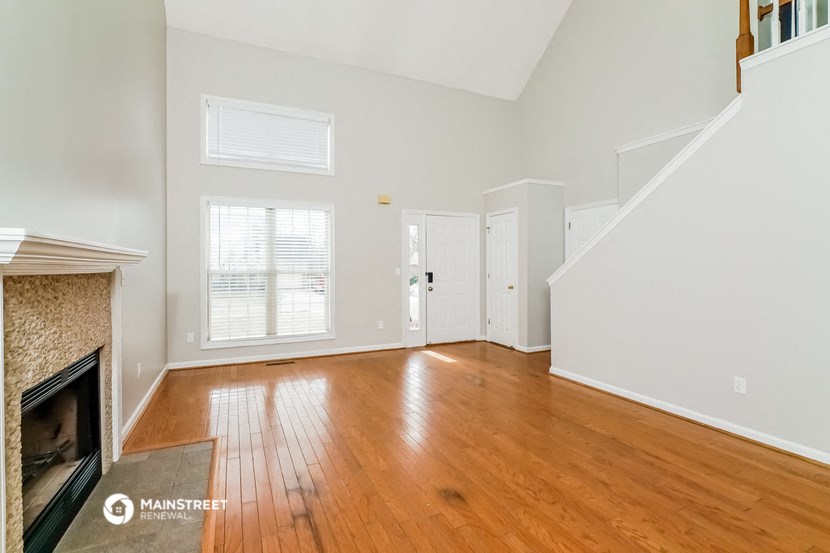 an empty living room with a fireplace and wood flooring