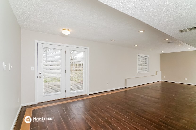 the living room and dining room of an apartment with wood floors and white walls