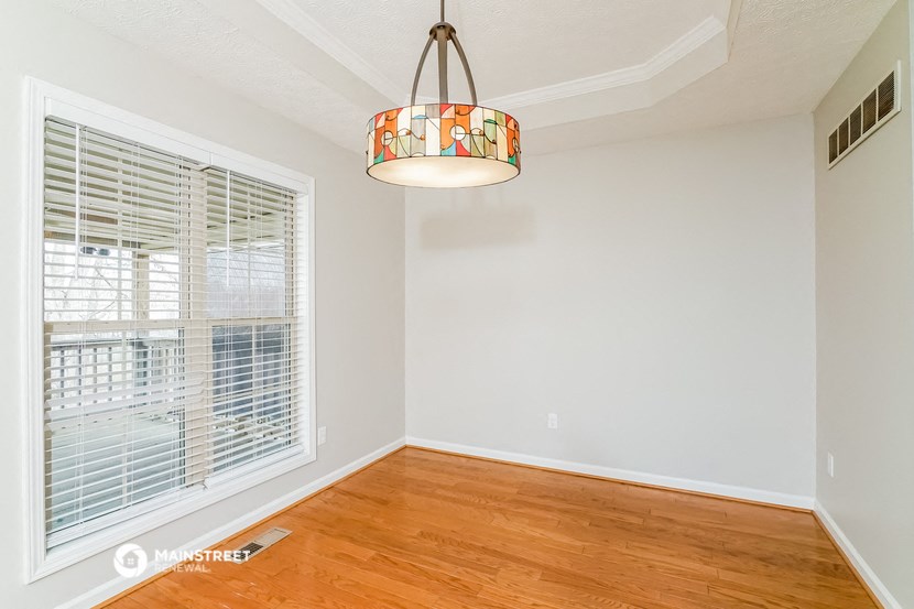 an empty living room with a large window and a light fixture
