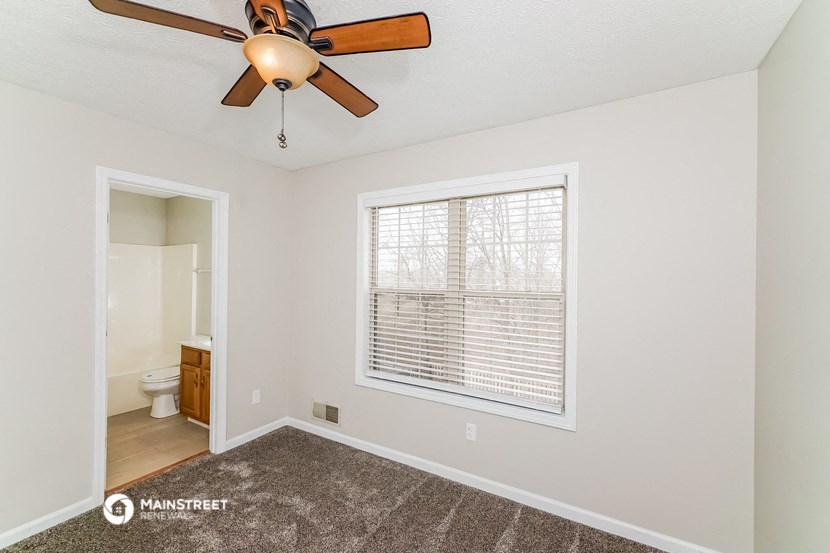 the spacious living room has a large window and a ceiling fan