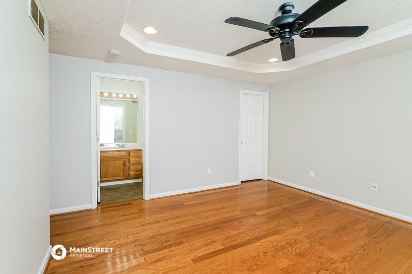 an empty living room with wooden floors and a ceiling fan