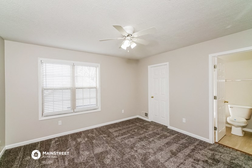 the master bedroom has a ceiling fan and a door to the bathroom