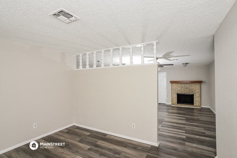 an empty living room with a fireplace and a ceiling fan