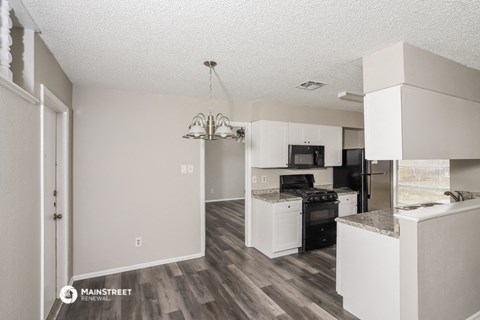 a renovated kitchen with white cabinets and a black stove and refrigerator
