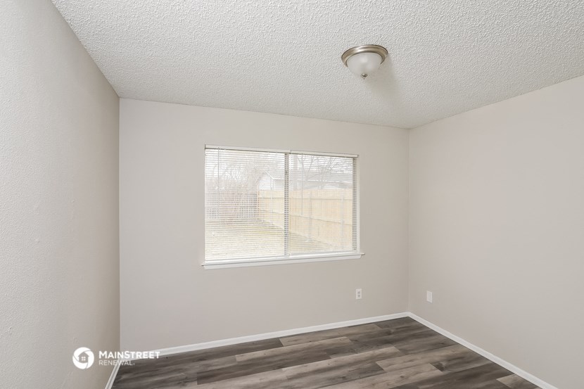 a bedroom with a large window and wood flooring
